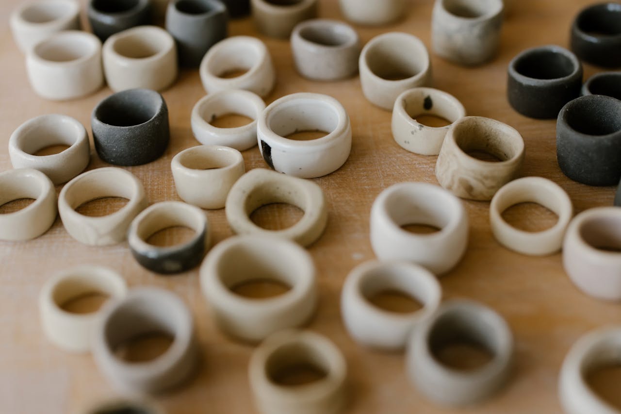 Variety of handcrafted ceramic rings in different colors arranged on a wooden table.