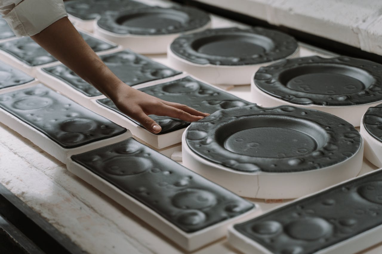 Artisan inspecting and touching black ceramic plates during crafting process.